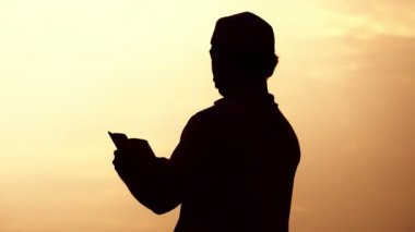 Asyalı Müslüman adamın silueti dua ediyor. 