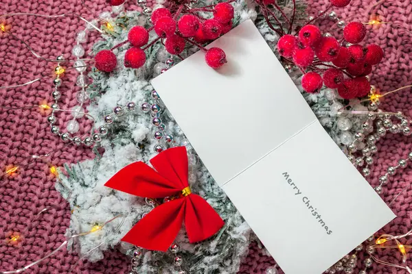 Üzerinde kırmızı fiyonklu süveter ve Noel ağacı ve tatil ışıkları olan bir Noel kartı.