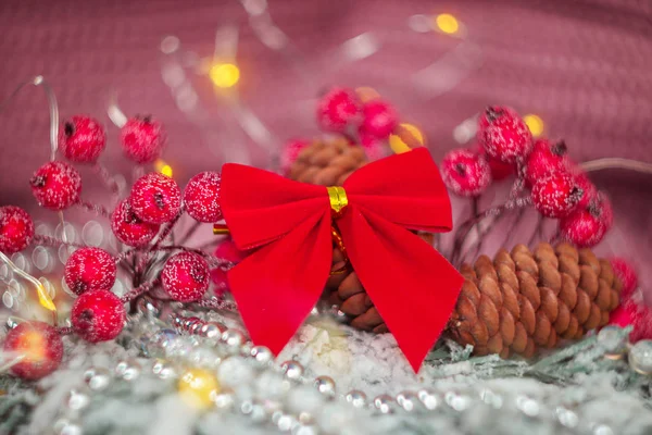 Fake plant of pine needles, red bow pine cone and red berries for Christmas home decoration.