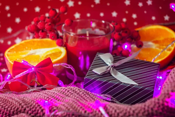 Noel konsepti. Bulanık tatil ışıkları. Noel kartı. Hediye kutusu, portakallar, mum ve fiyonklar sıcak süveter ve kırmızı noktalı arka plan