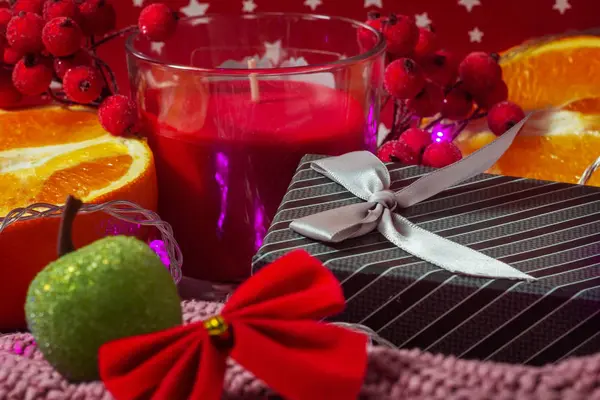Noel konsepti. Bokeh tatil ışıkları. Yeni yıl kartı. Hediye kutusu, portakallar, dekoratif elma ve kalın süveter ve kırmızı noktalı arka plan