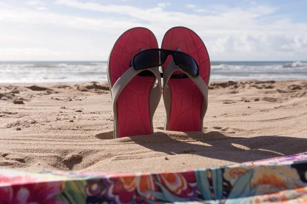 Par chinelos com óculos de sol na areia da praia — Fotografia de Stock