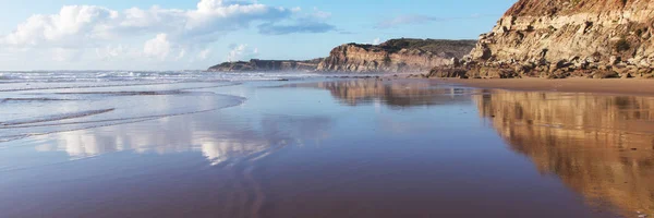 Montanha refletida na água suave da praia Areia Branca. Lourinha, Portugal — Fotografia de Stock