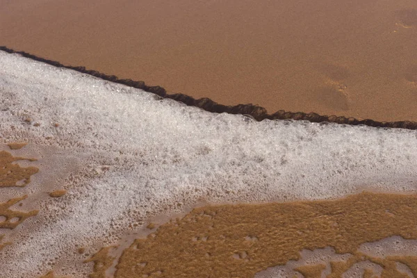 Onda com espuma na praia de areia — Fotografia de Stock