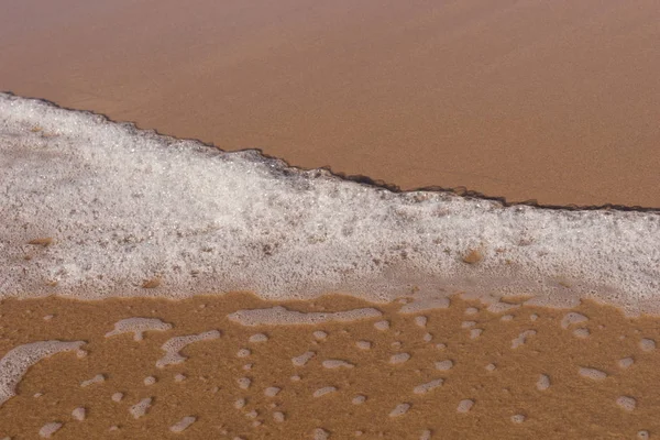 Onda com espuma na praia de areia — Fotografia de Stock