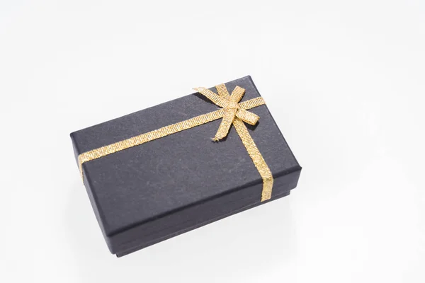 Scatola regalo nera con nastro in oro isolato — Foto Stock