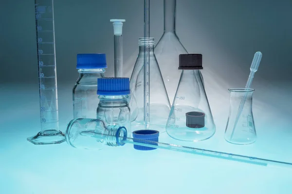Стеклянные лабораторные приборы на голубом столе — стоковое фото