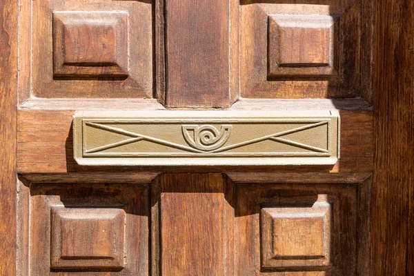 Closeup of letter box in wooden door