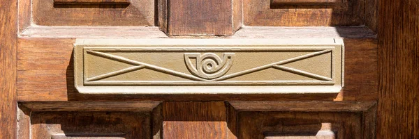 Closeup of letter box in wooden door