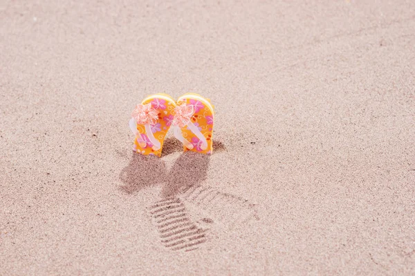 Chanclas de colores con flores en la playa — Foto de Stock