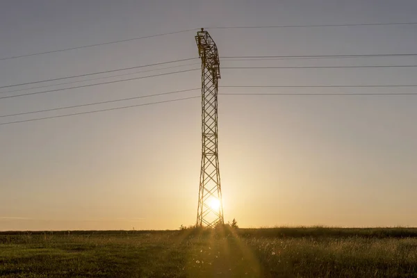 Hoogspanning lijnen en pyloon in sunrise — Stockfoto