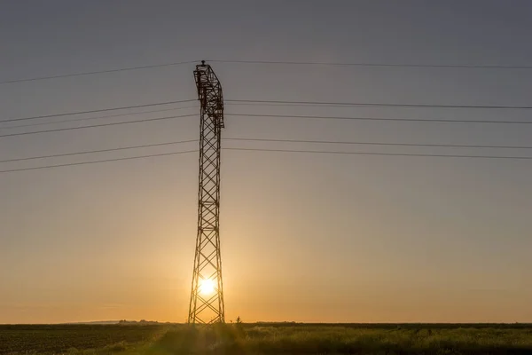 Hoogspanning lijnen en pyloon in sunrise — Stockfoto