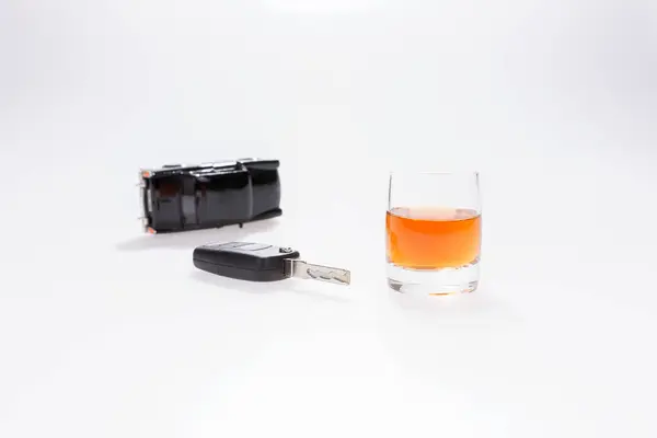 Car keys next to a glass of brandy Stock Photo