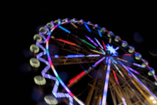 Roda gigante à noite com um borrão de movimento e flares da lente — Fotografia de Stock