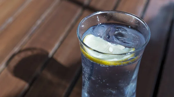 Стакан воды с ломтиком лимона и кубиком льда на столе — стоковое фото