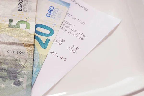 Restaurant bill with euro bills on a plate in Germany