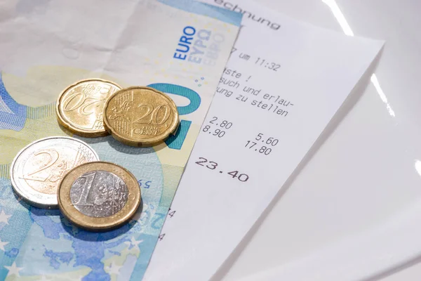 Restaurant bill with euro bills and coins on a plate in Germany