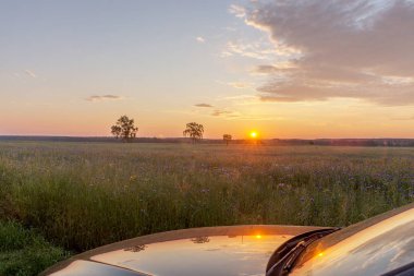 Yaz aylarında gündoğumu yansıması ile siyah araba