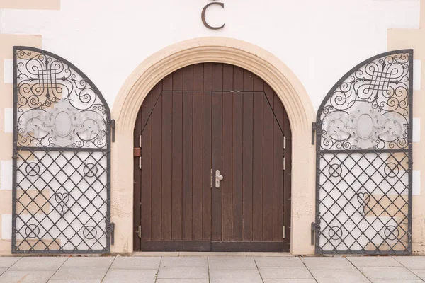 Entrance with an arched double door, made from hard wood with metal frame
