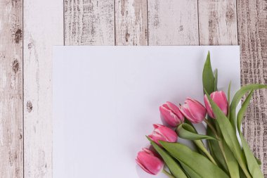 Ahşap zemin ile boş bir beyaz kart üzerine Pembe Laleler