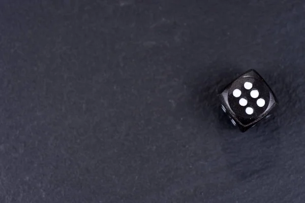 黑色背景下的单一黑色骰子 六边立方体与白色点 — 图库照片