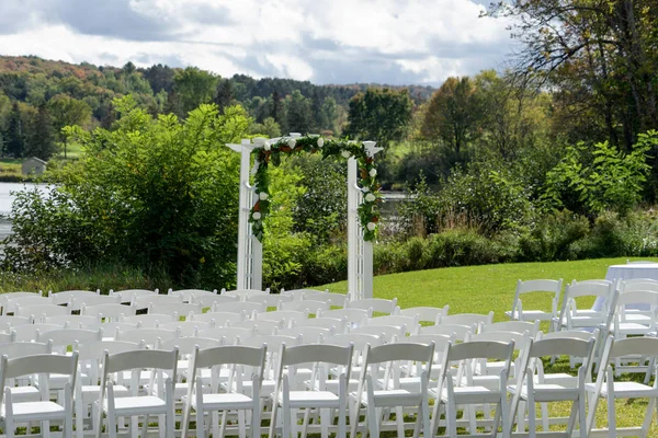 Place for wedding ceremony outdoor. Wedding arch decorated with flowers and white chairs