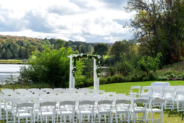 Place for wedding ceremony outdoor. Wedding arch decorated with flowers and white chairs