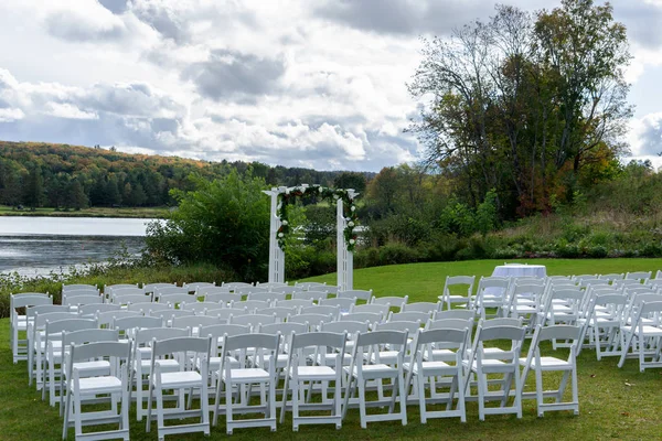 Place for wedding ceremony outdoor. Wedding arch decorated with flowers and white chairs