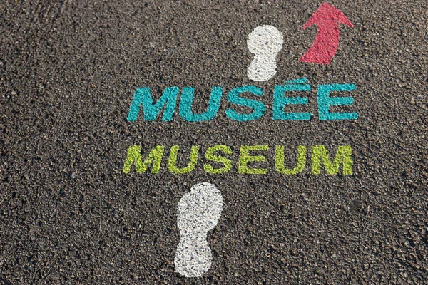 Word Museum written in English and French on the asphalt. Directional display for the visitors