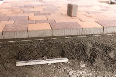 Yeni renkli kaldırım taşları düz bir yüzey üzerinde yönlendirme kablosu boyunca.