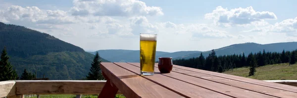 Glass beer on the table in the outdoor restaurant, mountains in the background