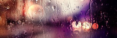 Panoramik görüntü. Bulanık araba ışıkları. Ön camda yağmur damlaları
