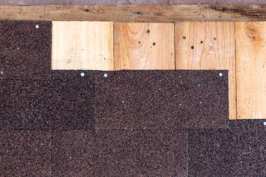 Ahşap panellere çivilenmiş kırmızı ve siyah bitumen kiremitler