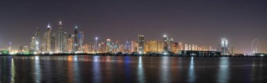 Gece Dubai gökyüzü manzaralı, suda ışık yansımaları var.