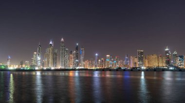 Dubai gece manzaralı Jbr bölgesinden gökdelenler ve su üzerinde ışık yansımaları