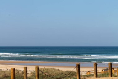 Dalgalar, sahil, okyanus ve mavi gökyüzü güneşli bir günde çekiliyor. Rahatlamak için seyahat cenneti.  