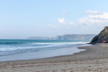 Dalgalar, sahil, okyanus ve mavi gökyüzü güneşli bir günde çekiliyor. Rahatlamak için seyahat cenneti.  