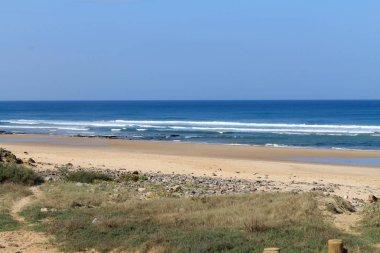 Dalgalar, sahil, okyanus ve mavi gökyüzü güneşli bir günde çekiliyor. Rahatlamak için seyahat cenneti.  