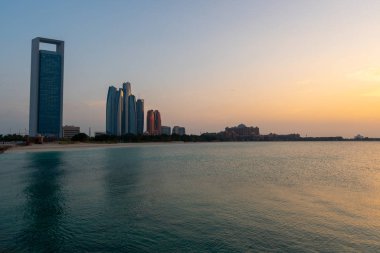 Abu Dabi geceleri ufuk çizgisi suyun üzerinde ışık yansımaları ile. Gün batımında çekilmiş.. 