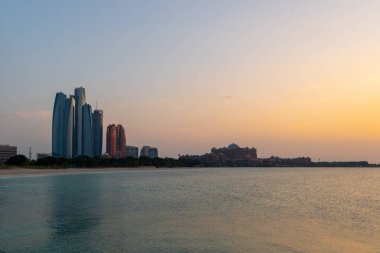 Abu Dabi geceleri ufuk çizgisi suyun üzerinde ışık yansımaları ile. Gün batımında çekilmiş.. 