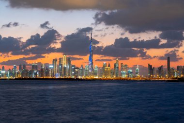 Dubai / BAE - 01 27 2020 Dubai 'nin ikonik binalarının üzerinde güzel bir günbatımı. İnanılmaz gri bulutlar ve turuncu renkli gökyüzü. Dubai Creek 'ten modern ve lüks şehir manzarası.