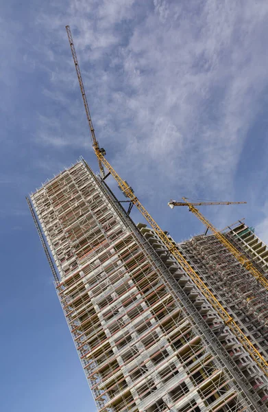 skyscrapers are being built for more living spaces in cities,  using construction techniques and cranes