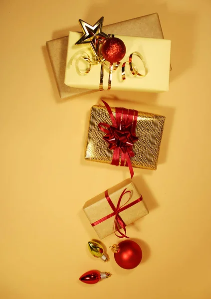 Composición de cajas de regalo de Navidad decoradas con oropel dorado, destellos, bolas rojas y arcos sobre un fondo beige . — Foto de Stock
