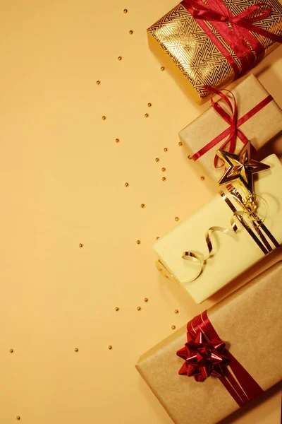 Composición de cajas de regalo de Navidad decoradas con oropel dorado, destellos, bolas rojas y arcos sobre un fondo beige . — Foto de Stock