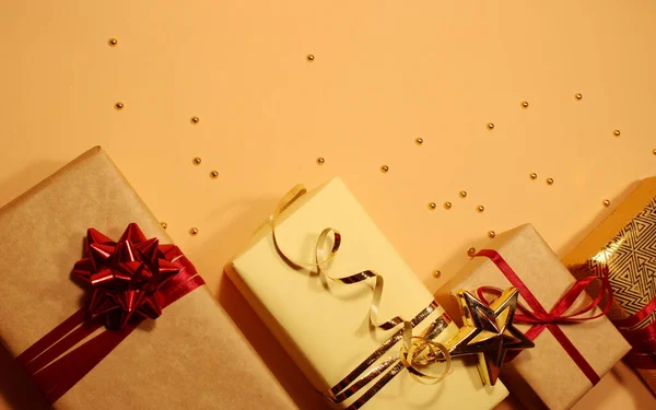 Composición de cajas de regalo de Navidad decoradas con oropel dorado, destellos, bolas rojas y arcos sobre un fondo beige . — Foto de Stock