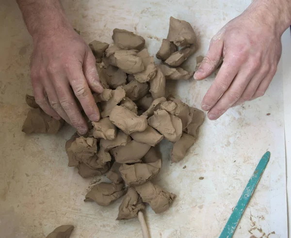 Mains de sculpteurs modelant un bloc d'argile sur une table blanche — Photo