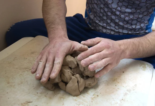 Sculptors hands modelling a block of clay on a white table — Stock Photo, Image
