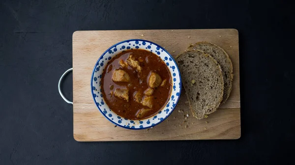 Stew with meat in a bowl. Dark background, top view.