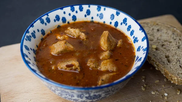 Stew with meat in a bowl. Dark background, top view.