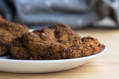 Tahta bir masanın üzerinde beyaz bir tabakta duran bir balığın yakın plan çekimi.